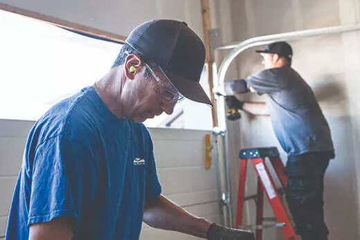 Two garage door technicians working on garage door